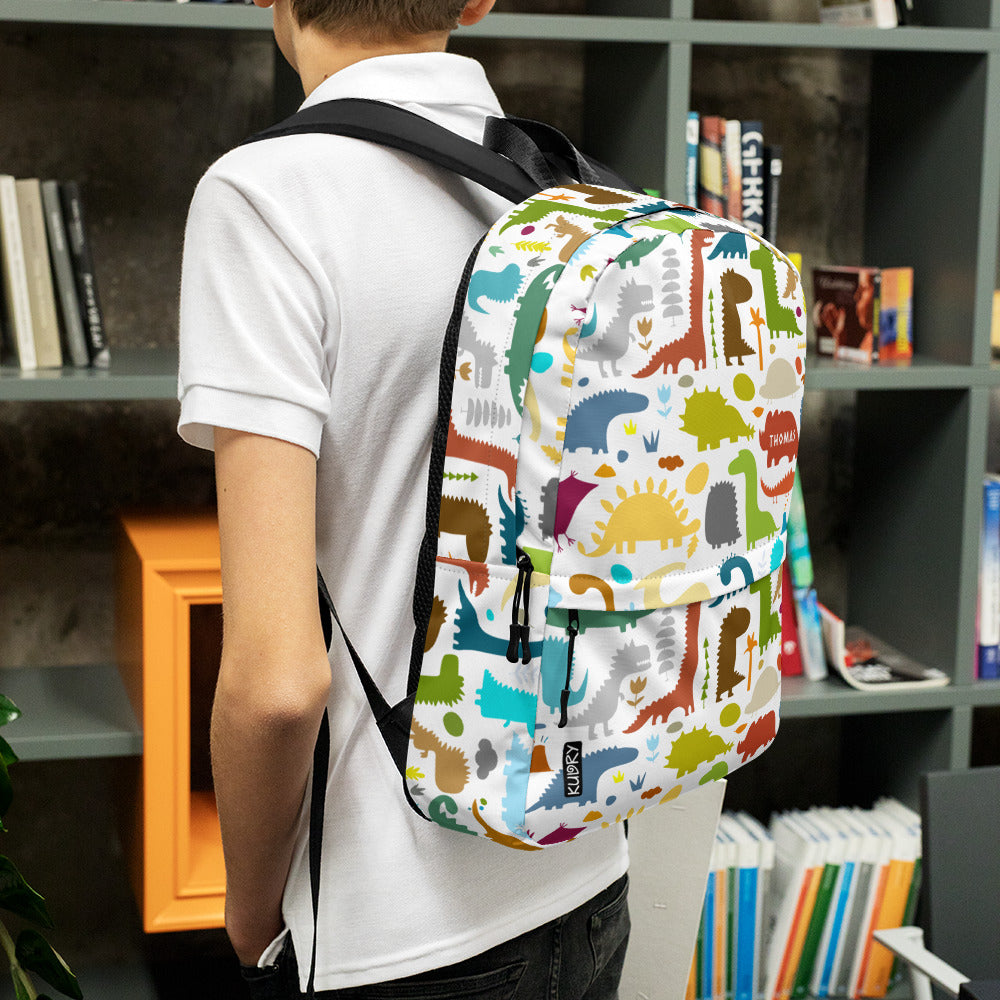 Boy in library with Paleontology Backpack white with colorful Dinosaurs designer print and personalised text