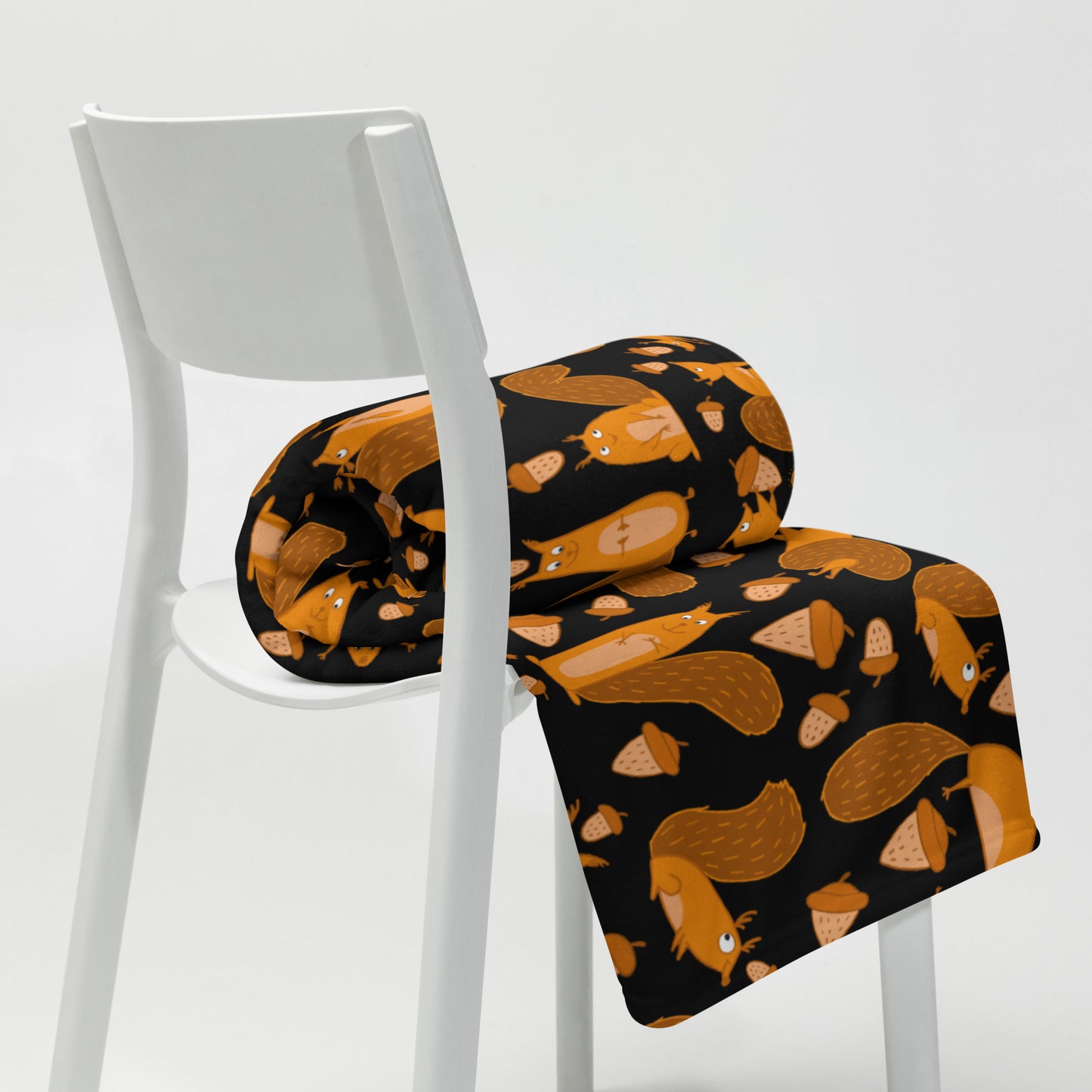 Throw blanket black color with funny orange squirrels and nuts on chair