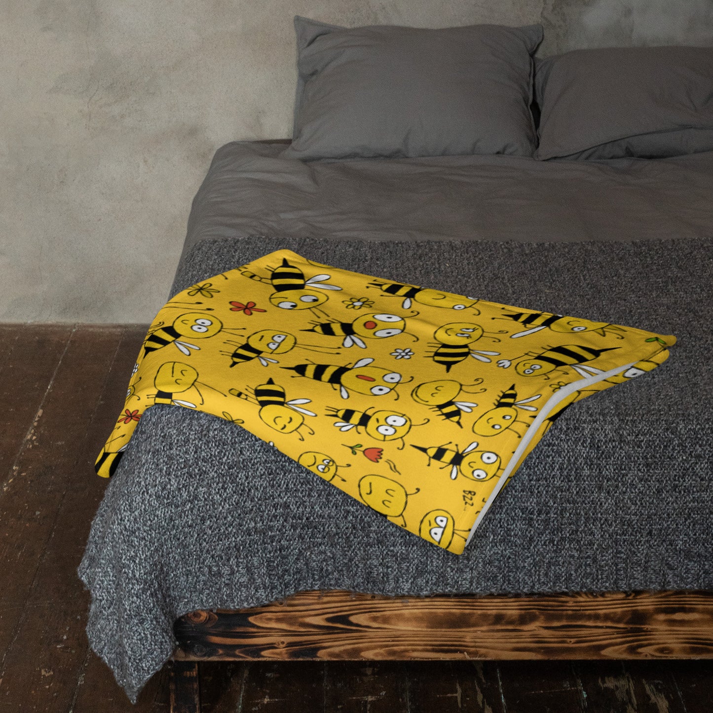 Yellow blanket with bee pattern on a gray bed
