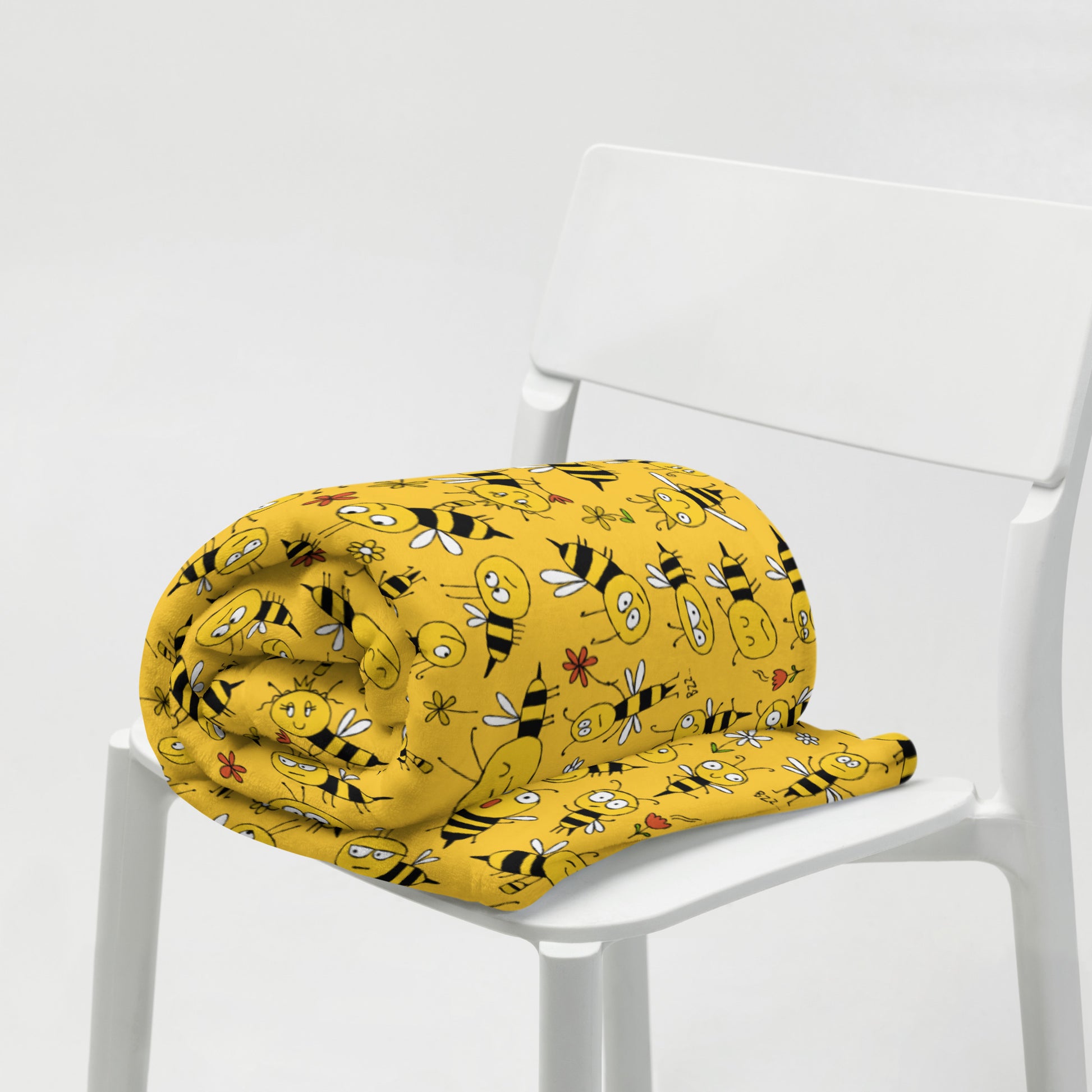 Yellow blanket with bee pattern on a white chair